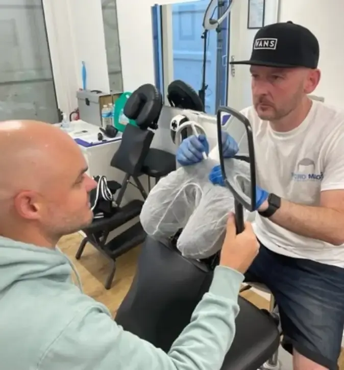 Stuart showing a client the result in a hand mirror at the Micro Magic clinic